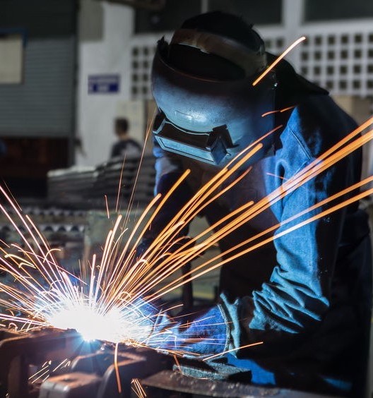 Welder welding metal in workshop with sparks