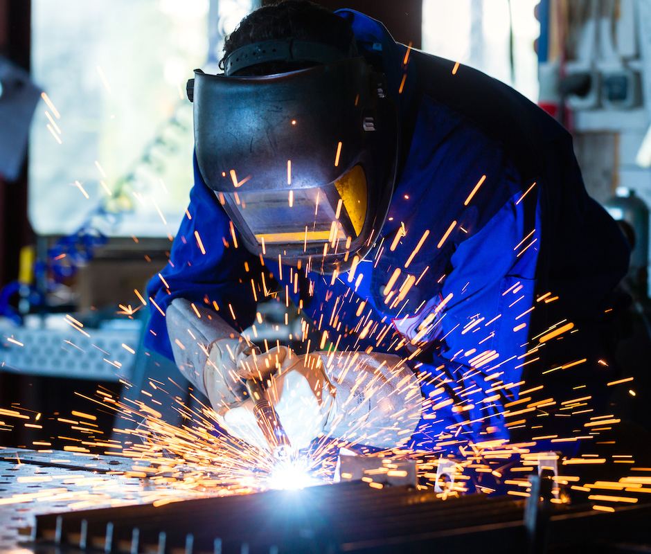 Welder welding metal in workshop with sparks
